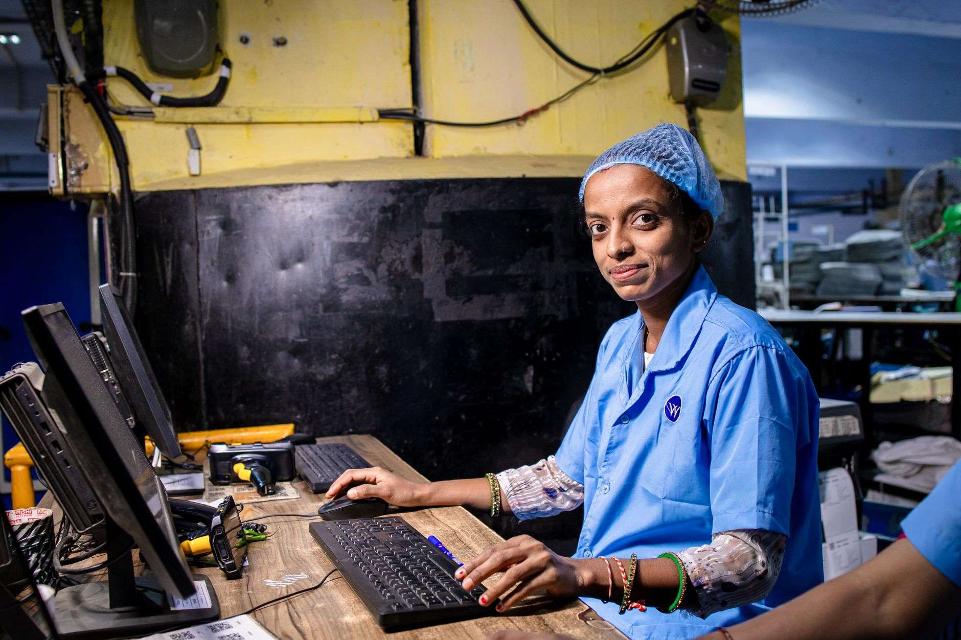 A factory worker at an electronics assembly line — the human labour underpinning the hardware and supply chains that power AI, rarely visible in debates about AI power and openness.